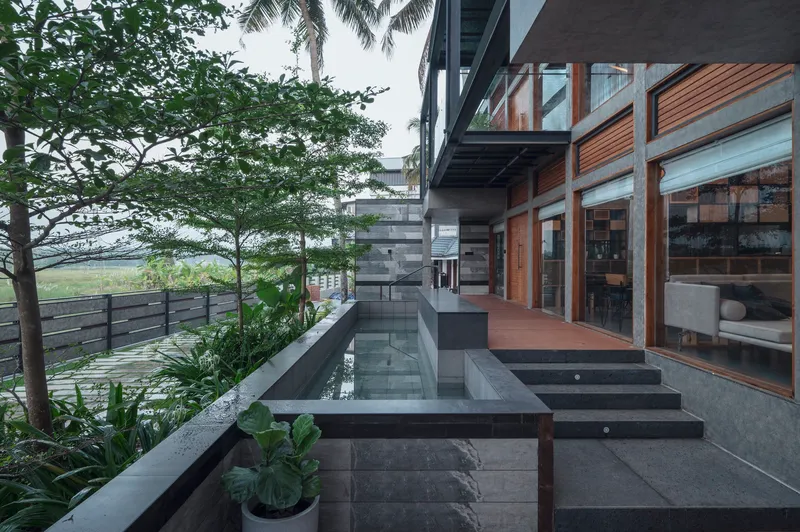 Stepped terrace with dark stone slabs and shallow water channel alongside timber and glass facade