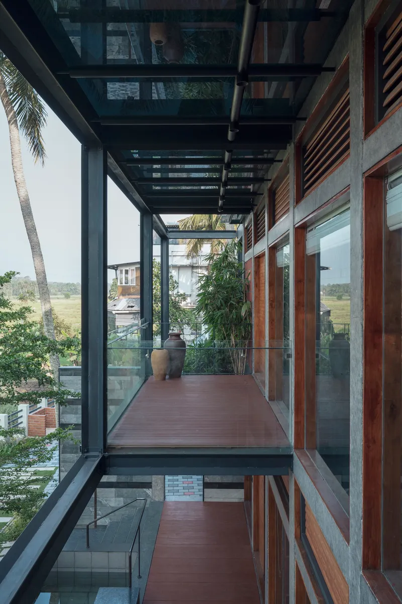 Covered walkway with steel pergola overhead and timber decking bridging between glazed volumes