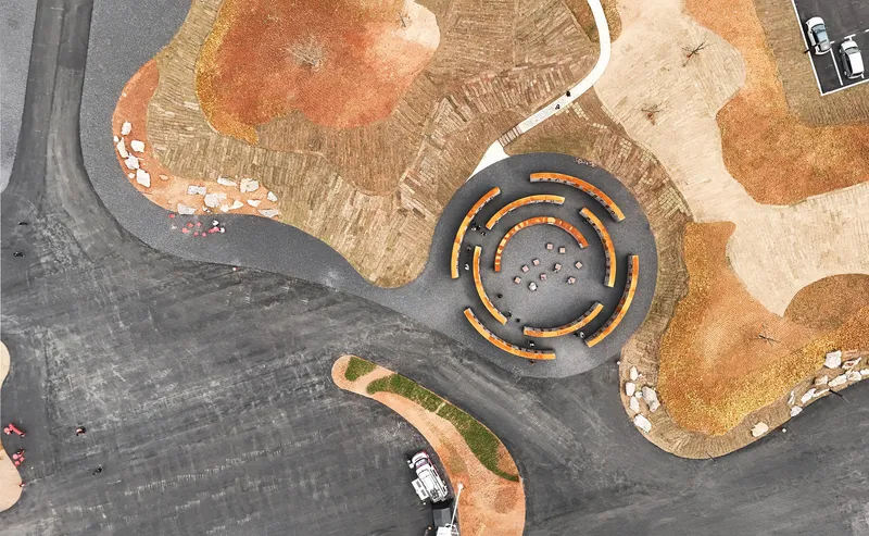 Aerial view showing a circular courtyard with concentric seating rings surrounded by parking and landscaped areas