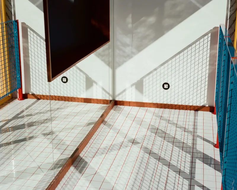 White grid tile floor receiving sharp diagonal shadows from an adjacent window