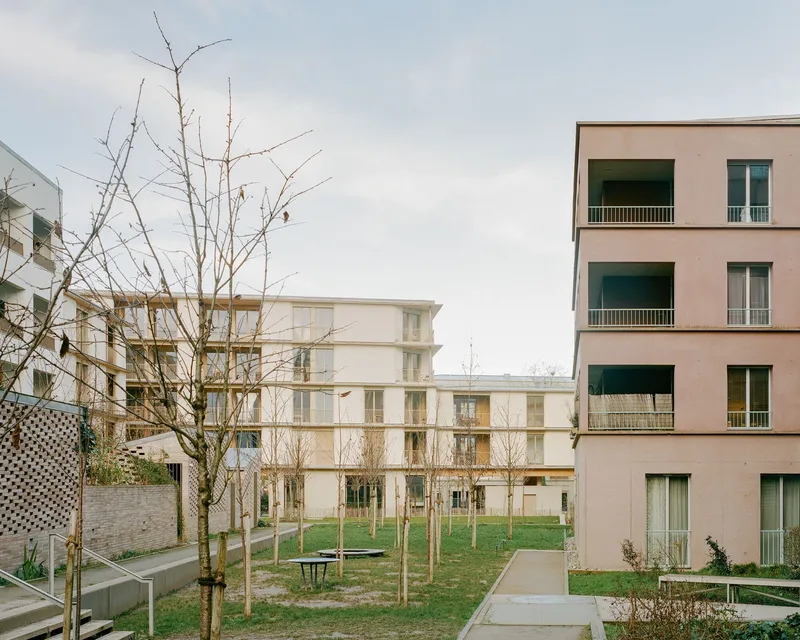 Courtyard view with pathways and bare winter trees between pale facade blocks