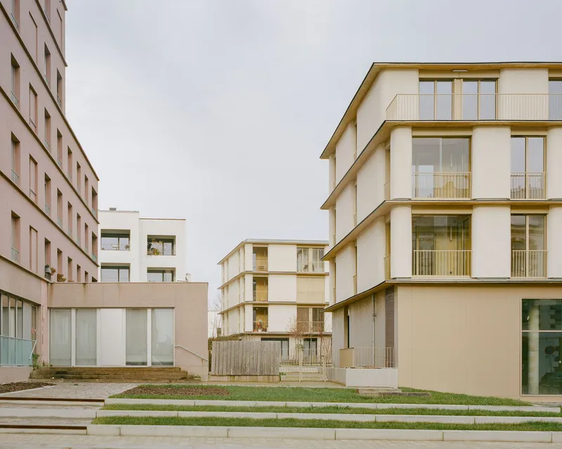 View across terraced lawn steps toward multiple residential blocks with timber trim and balconies