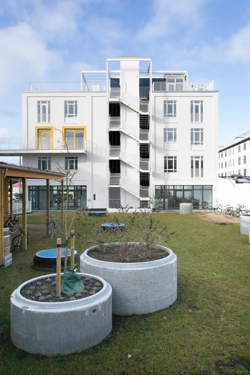 Courtyard with circular concrete planters and exterior staircase ascending the white facade
