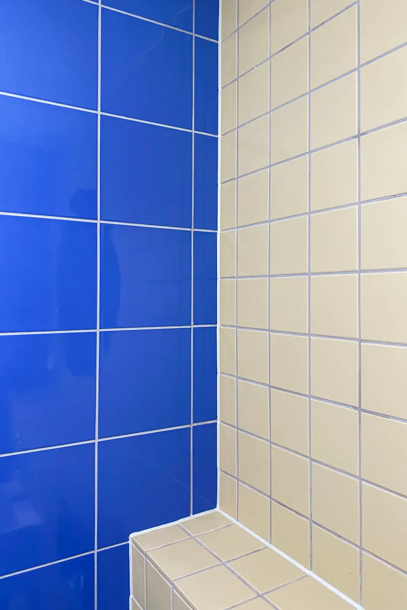 Bathroom corner with cobalt blue and cream tiles meeting at a white-grouted edge