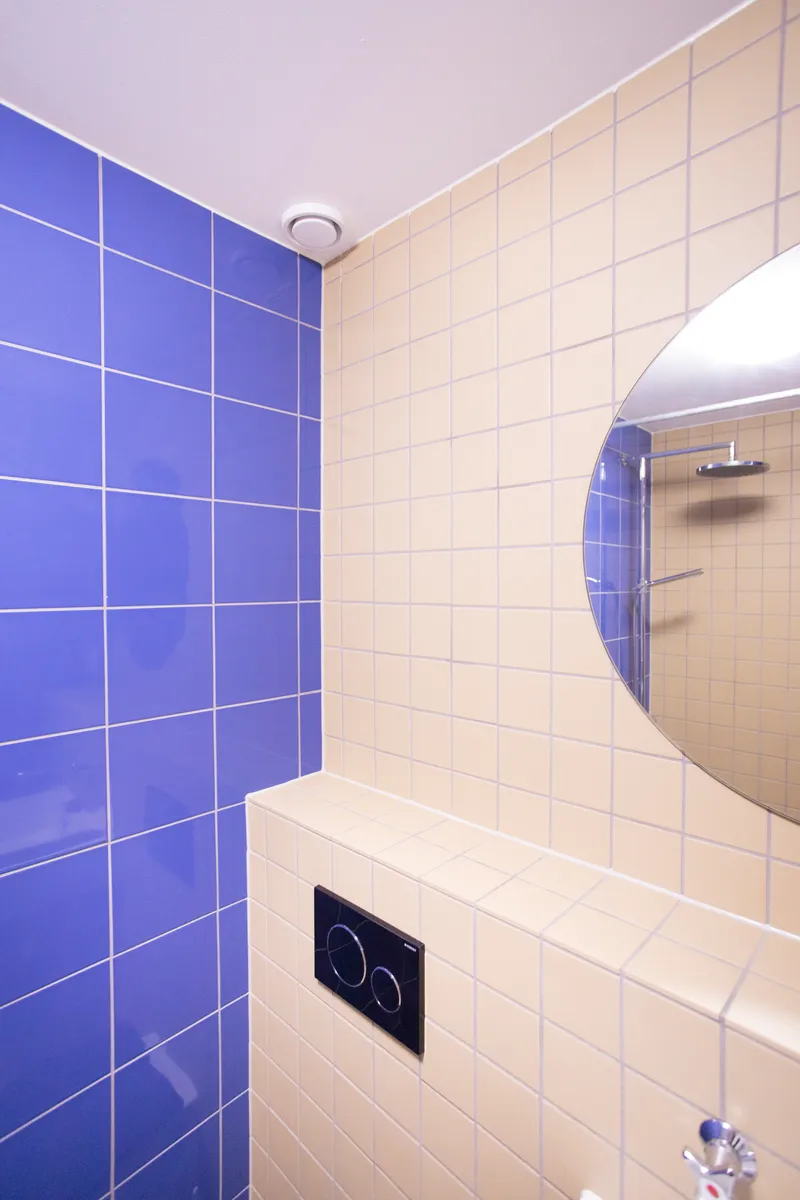 Bathroom corner with blue and white square tiles meeting at a curved edge