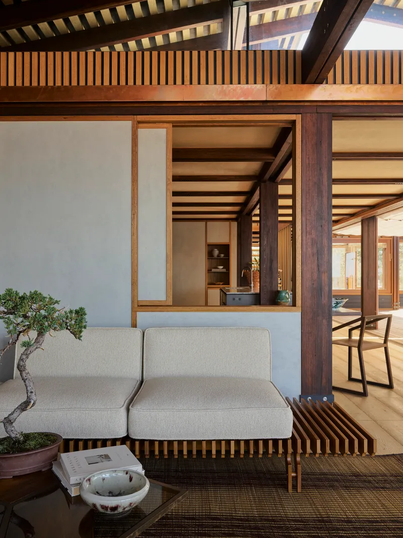 Covered seating area with slatted timber bench and exposed beam ceiling looking through to interior spaces