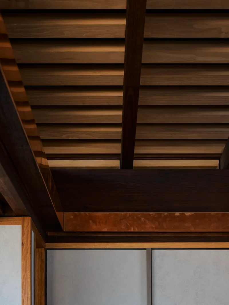 Detail of horizontal wood slat ceiling with exposed timber beams and dark steel beam junction