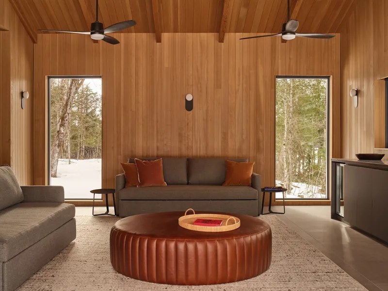 Seating area with timber ceiling, twin ceiling fans, and tall windows opening to snowy landscape