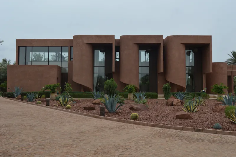 Street view of the repeating lobed facade modules with glazing and xeriscape planting below an overcast sky