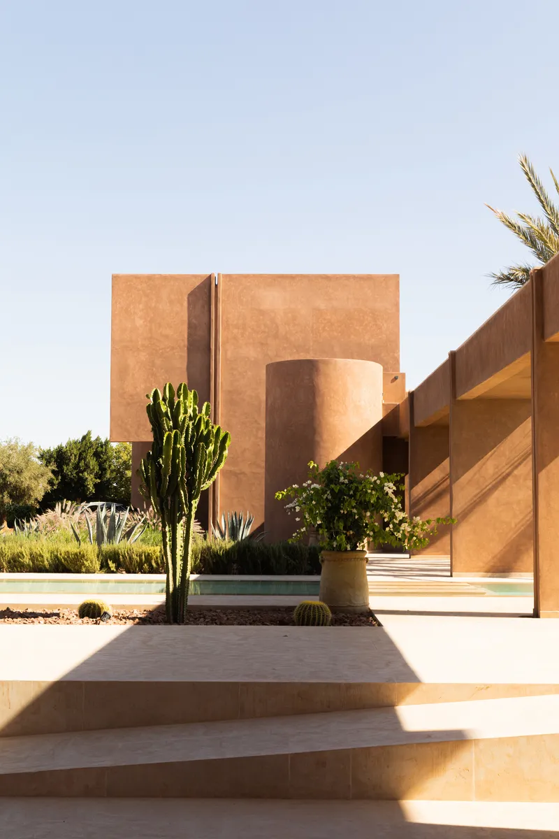 View of the rammed earth facade with planted cactus and agave in the desert landscape
