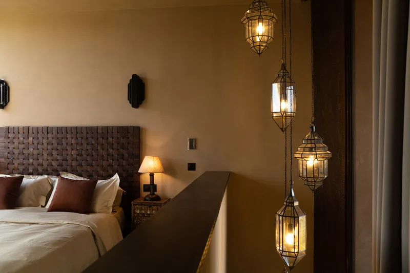 Bedroom interior with woven leather headboard and four suspended lanterns glowing in warm light