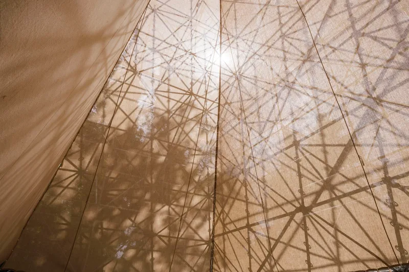 Translucent fabric wall with geometric structural shadows visible through the material in bright sunlight