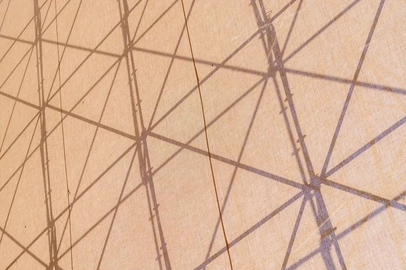 Detail of triangulated shadow pattern cast by structural framework onto a taut beige membrane