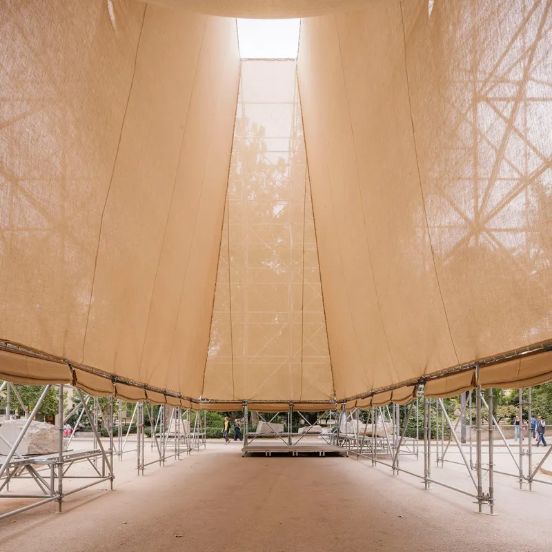 Interior view beneath the tensile fabric canopy with tubular steel scaffolding and a central skylight opening