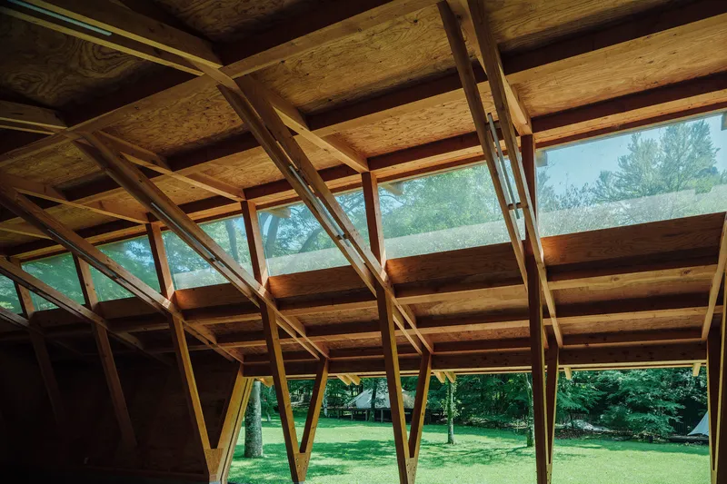 Upward view of the angled timber rafters and clerestory windows bringing daylight through the roof