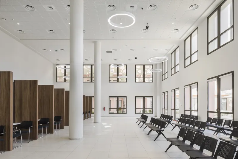 Double-height lobby with white columns, timber privacy screens and rows of seating