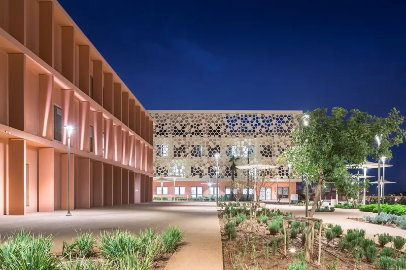 Courtyard view showing perforated screen facade opposite terracotta louvered facade at night