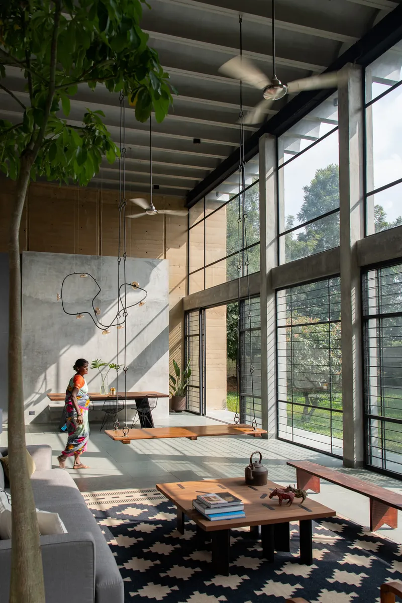Interior view with person walking past the dining area as sunlight filters through steel-framed windows