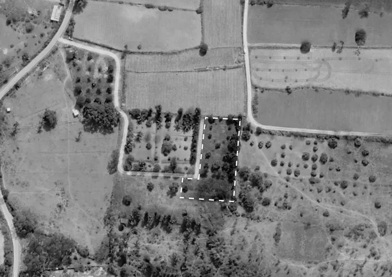 Aerial photograph showing the compound outlined in white amid agricultural fields and scattered tree groves