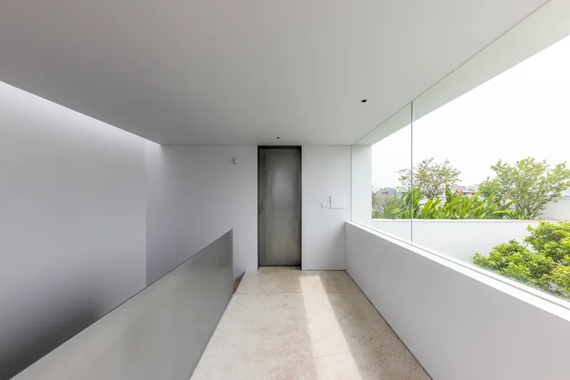 Upper-level corridor with terrazzo flooring and a horizontal window overlooking garden canopy