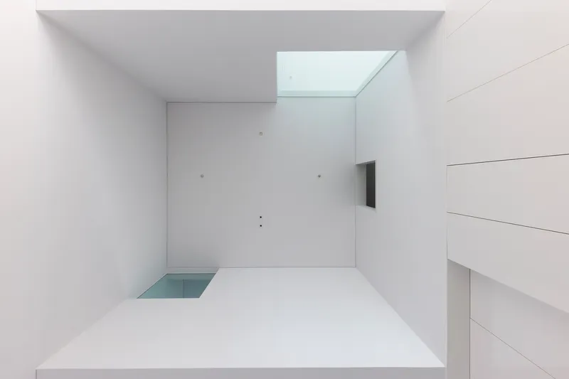 Looking up at white ceiling with recessed skylight and floating white panel above minimal floor outlet