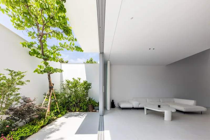 Interior terrace opening with retractable glass doors and planted courtyard garden under open sky