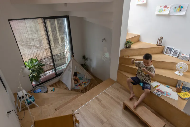View down to the timber platform where a child sits drawing near a window
