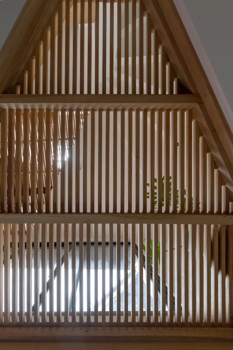Close-up of the triangular timber slat screen with light filtering through vertical members