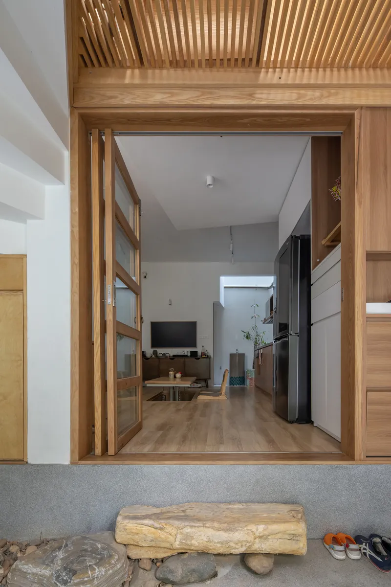 Threshold view through timber-framed sliding doors showing the slatted ceiling and living space beyond