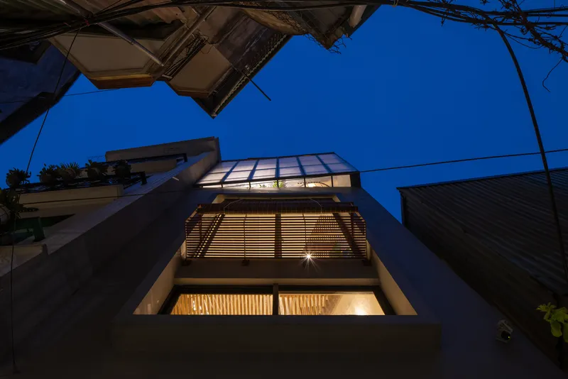 Upward view of the illuminated facade with horizontal timber louvers and glazed skylight at twilight