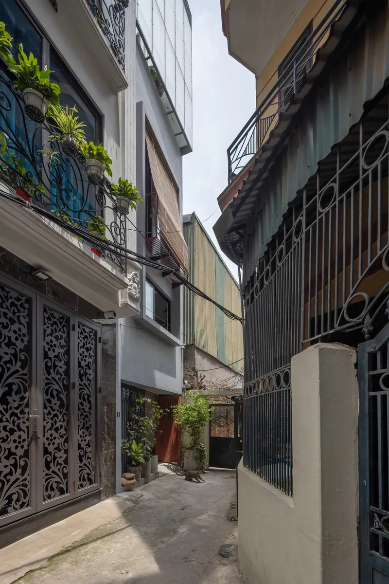 Narrow alleyway view between neighboring facades with ornamental metalwork and planted balconies