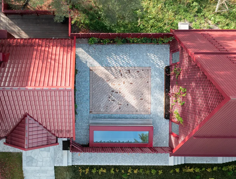 Overhead view of tiled courtyard with chevron pattern framed by red gabled roofs and garden trees