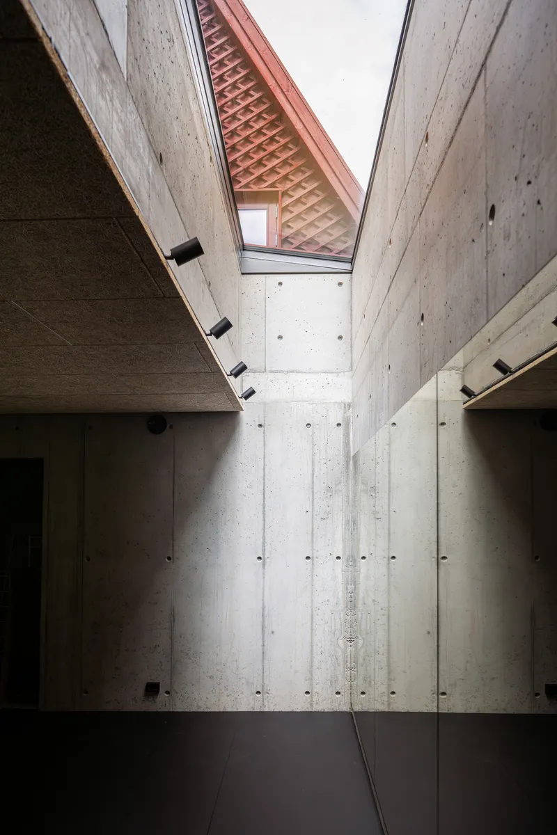 Concrete corridor with skylight showing terracotta brick vault under an overcast sky