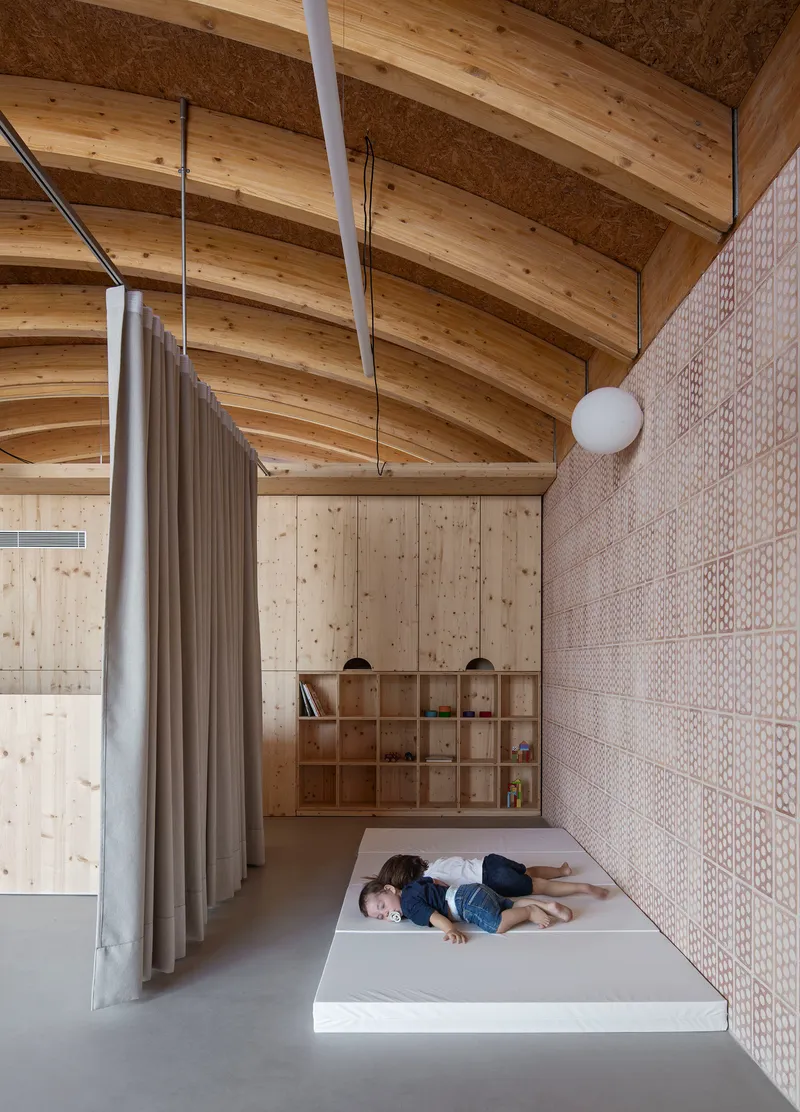 Raised platform with timber storage cubbies and a grey curtain divider under curved timber ceiling