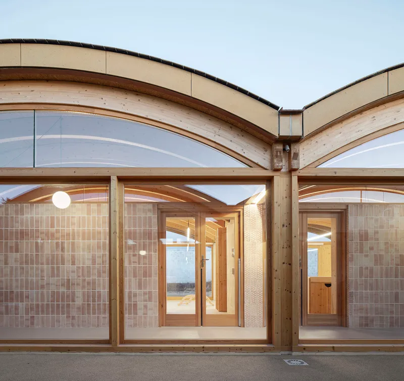 Arched timber-framed openings forming a corner junction with patterned screen walls at twilight