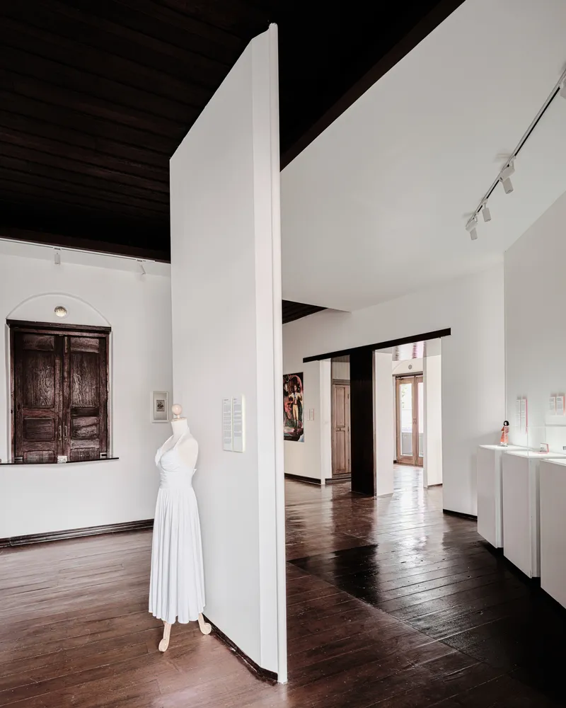 Freestanding white partition wall with a dress form displayed and dark timber ceiling above