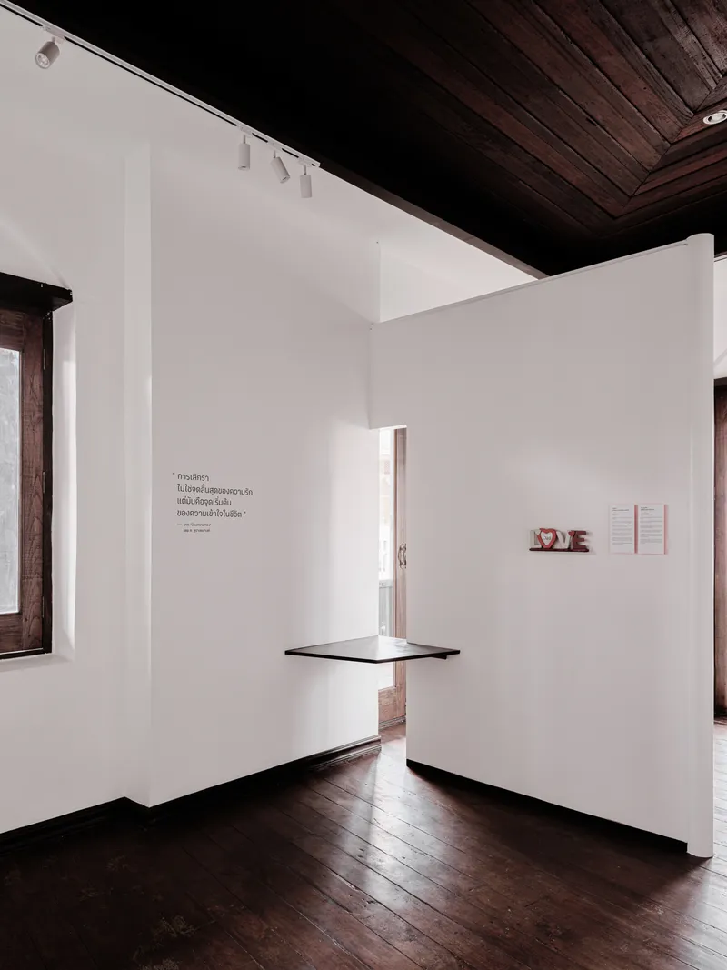 Narrow vertical opening in a white partition wall with a floating shelf and dark flooring