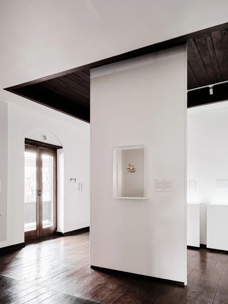 Framed artwork on a white partition wall with angular dark timber ceiling plane above