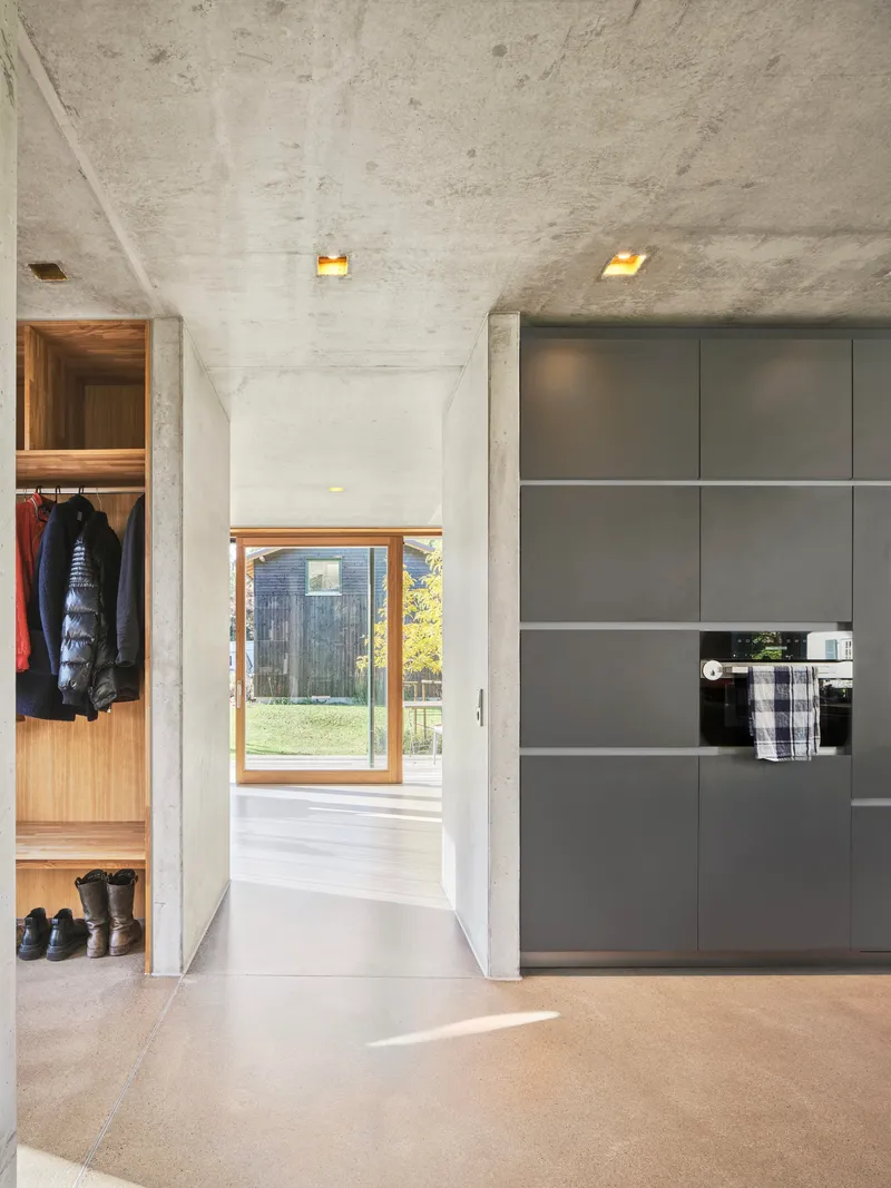 Kitchen passage with gray cabinetry and concrete ceiling lit by recessed skylights