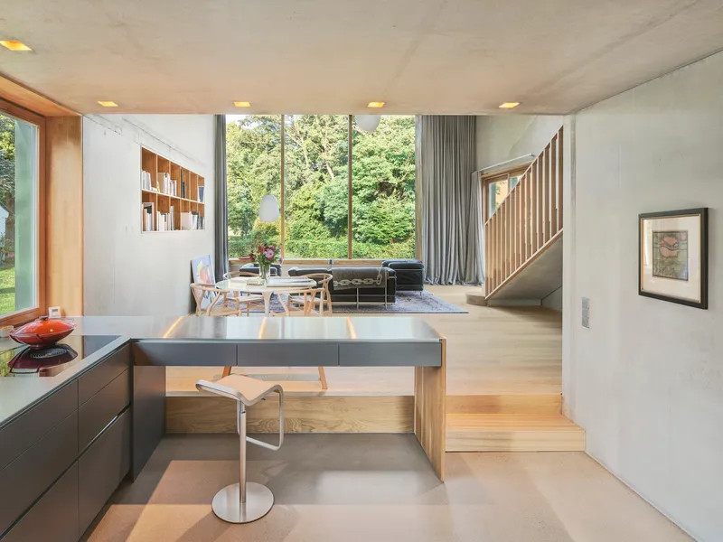 Split-level interior with timber-slatted staircase connecting kitchen island to upper living area
