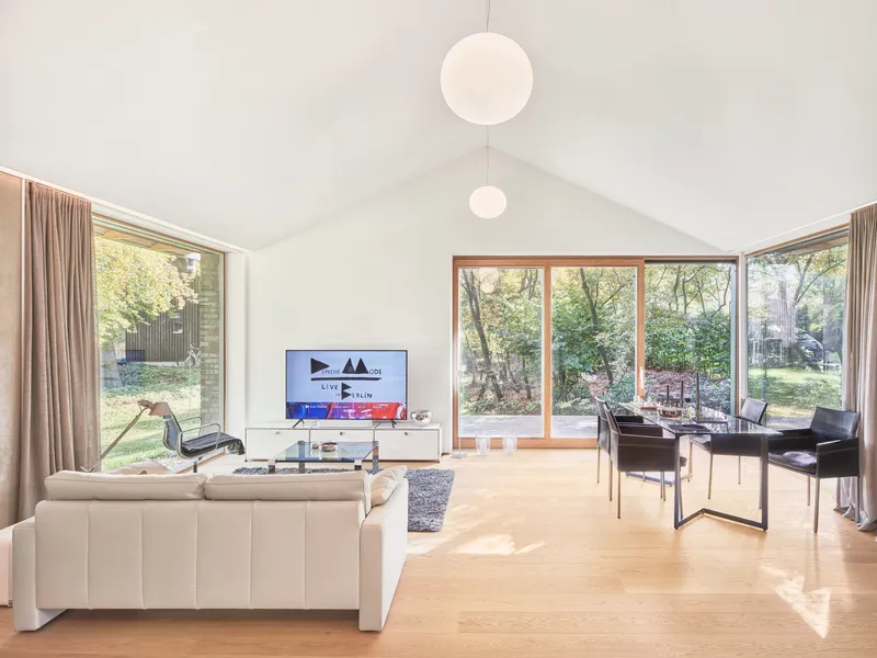 Vaulted living space with pitched ceiling and glazed doors opening onto a wooded garden