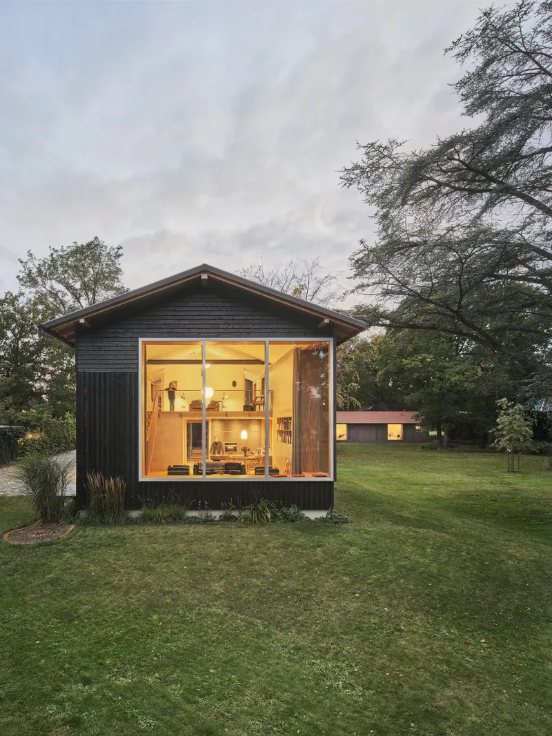 Gabled studio volume with full-height glazing and dark timber cladding at twilight