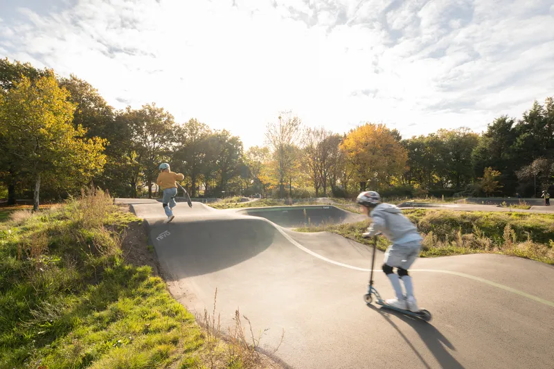 Concrete skate bowl with children on scooters in golden afternoon light
