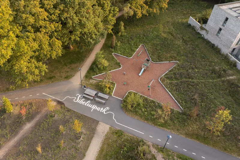 Overhead view of a star-shaped red rubber playground surface bordered with white edging and play equipment