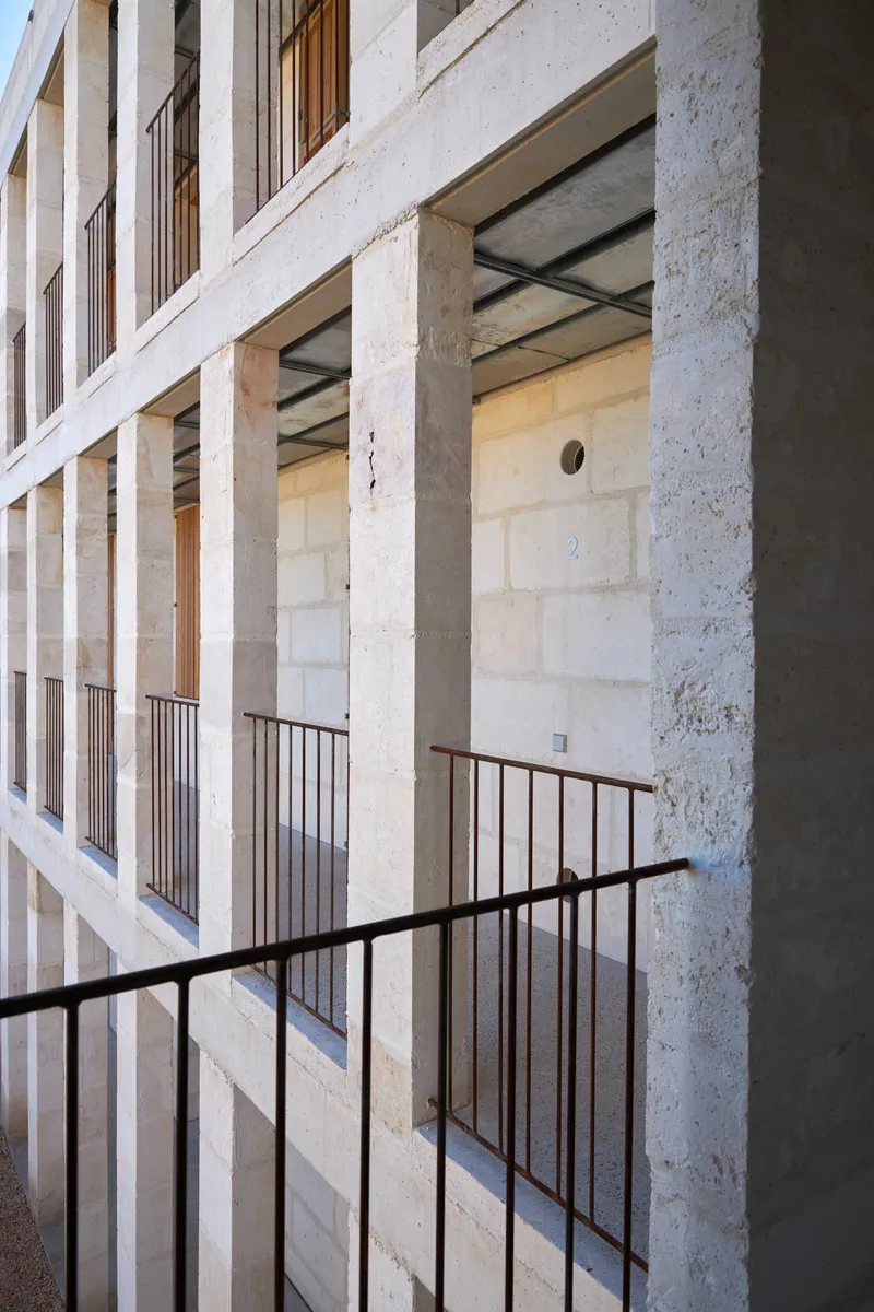 Steel railing on an outdoor balcony beneath deep concrete beam overhangs in afternoon sun