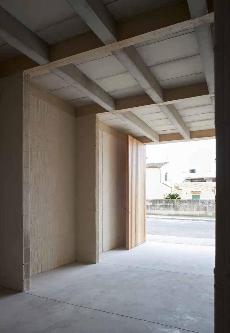 View through wide doorway with ribbed stone jambs and exposed concrete beam ceiling to the street beyond