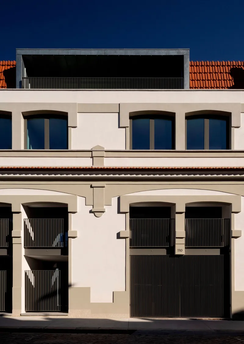 Street elevation showing arched window openings and recessed zinc-clad penthouse volume above terracotta roof
