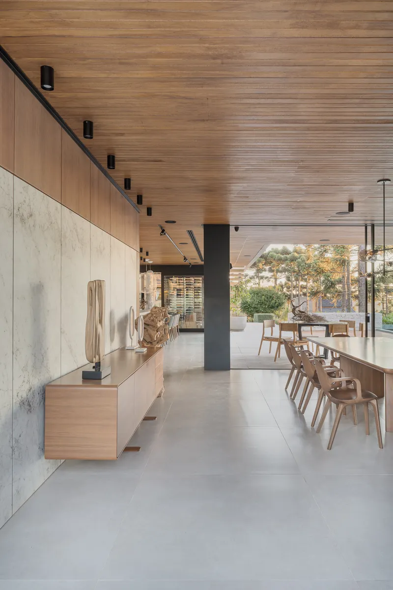 Open plan dining space with concrete floor and slatted wood ceiling extending toward glazed openings