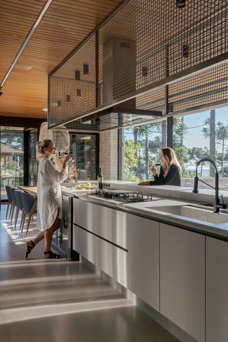Kitchen island with two people preparing food beneath suspended mesh screen and glazed facade