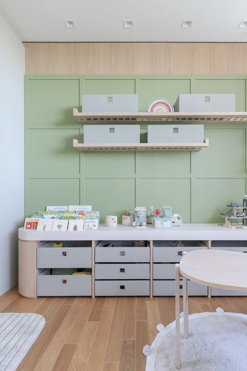 Storage wall with pale green cabinetry, floating timber shelves, and white countertop with open drawers